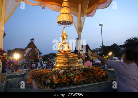 Thais gießt Wasser über Buddha-Statue während Songkran New Year Festival in Bangkok Stockfoto