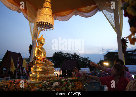 Thais gießt Wasser über Buddha-Statue während Songkran New Year Festival in Bangkok Stockfoto