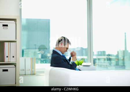 Traurig Geschäftsmann auf Sofa mit Telefonhörer im Büro sitzen Stockfoto