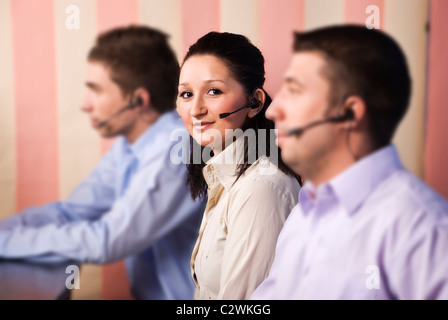 Nette junge Frau Kundendienstmitarbeiter suchen und Lächeln Sie in der Mitte zwei Männer-Team im Büro im Fokus Stockfoto