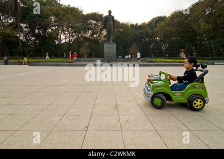 Horizontalen Weitwinkel von kleinen Kindern herumfahren Lenin Statue in Batterie betriebenen Autos im Lenin-Park, Zentrum von Hanoi Stockfoto