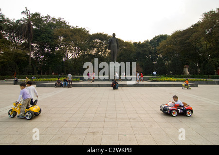 Horizontalen Weitwinkel von kleinen Kindern herumfahren Lenin Statue in Batterie betriebenen Autos im Lenin-Park, Zentrum von Hanoi Stockfoto