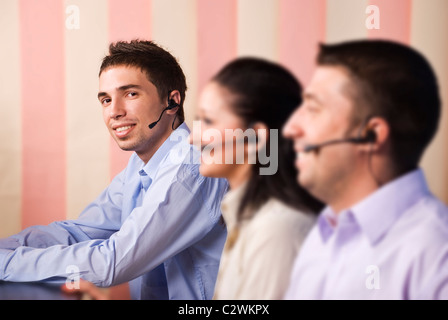 Call Center-Betreiber mit Kopfhörer, zwei Männer und eine Frau, die Arbeit in Büro, selektiven Fokus auf letzten jungen Mann Stockfoto