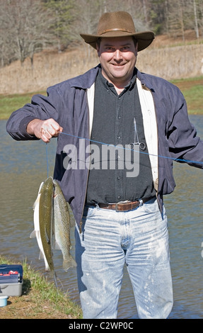 Mann an einem Teich mit seiner Wange frische Regenbogenforellen. Stockfoto