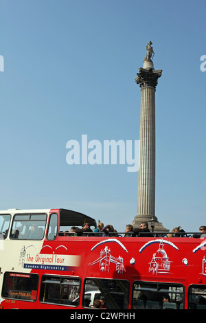 Ein Reisebus voller Touristen geht um Trafalgar Square mit der Nelson Säule im Hintergrund Stockfoto