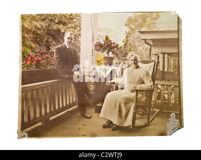 Ein Vintage Foto ein älteres Ehepaar sitzt auf der Veranda ihres Hauses. Sepia mit teilweise eingefärbt. Stockfoto