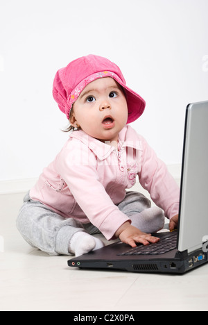 Geschäft Babymädchen am Boden sitzen, wegschauen und Laptop verwenden Stockfoto