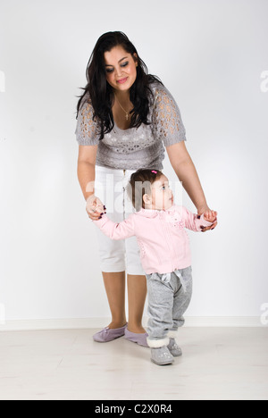 Junge Mutter hilft ihrem Babymädchen, um erste Schritte Stockfoto