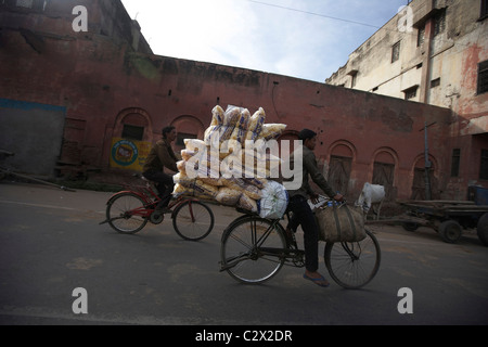 Mann auf Fahrrad mit schweren Last. Agra Straße Szene, Uttar Pradesh, Indien Subkontinent, Asien. Stockfoto