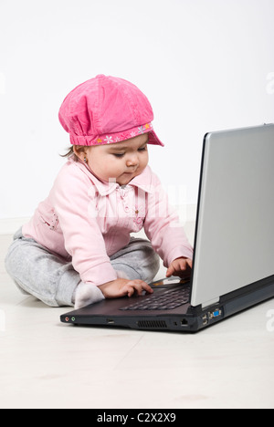 Babymädchen am Boden sitzen und arbeiten am laptop Stockfoto