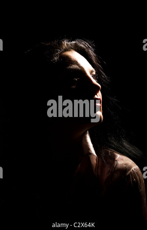 Porträt von schöne Brünette Frau Weg in der Dunkelheit mit weichem Licht auf ihr Gesicht schauen Stockfoto