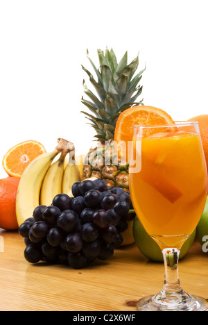 Frisch gepresster Orangensaft vor Bild mit verschiedenen Früchten im Hintergrund auf einem Holztisch Stockfoto