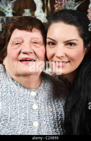 Porträt der schönen Oma und Enkelin mit ihren Gesichtern stehen einander und lächelnd in ein Wohnzimmer geschlossen Stockfoto
