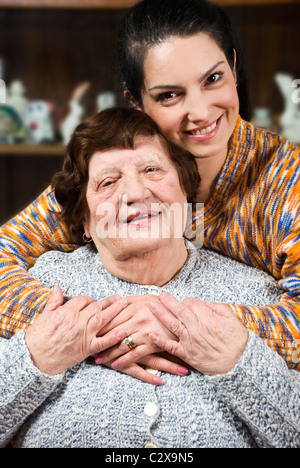 Enkelin gab eine Umarmung zu ihrer Oma lächelnd und halten ihre Hände zusammen Stockfoto