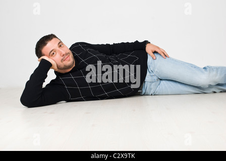 Cool Mann liegend auf weißen Holzboden und trägt einen schwarzen Pullover und jeans Stockfoto