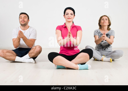 Drei Mitglieder einer Familie beim Yoga auf Holzboden in ihrem Haus Stockfoto