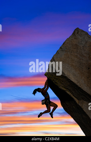 Weiblichen Rock Climber Kämpfe ihren nächsten Griff zu erreichen, wie sie ihren Weg kämpft oben eine steile Klippe. Stockfoto