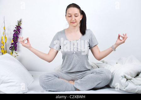 Junge Frau tut Yoga am Bett am Morgen Stockfoto