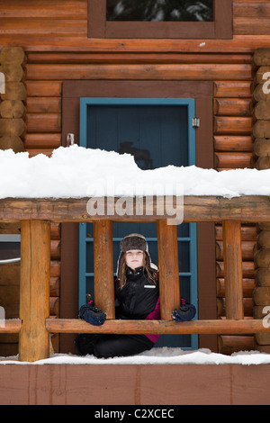 Kaukasische Mädchen sitzen auf verschneiten Veranda Stockfoto