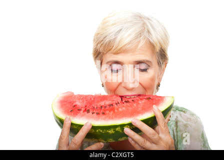 Nahaufnahme von senior Frau beißt ein Stück Wassermelone isoliert auf weißem Hintergrund Stockfoto