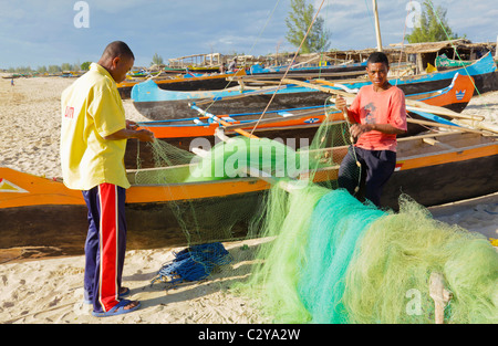 Zwei Vezo Fischer Flicken ihre Netze in Anakao Dorf im Südwesten Madagaskars vor ihren Pirogen. Stockfoto