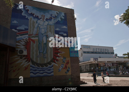 Die Menschen gehen durch ein Sowjet-Ära Wandbild zeigt eine heroische Persönlichkeit in Yuzhno Sakhalinsk, Sachalin, Russland Stockfoto