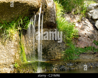 Wasserfall zwischen Felsen mit Vegetation an den Seiten Stockfoto