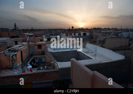 Marrakesch, Marokko, 15.04.2011. Blick über die Dächer im Zentrum von Marrakesch zeigt Frau bringt in ihre Wäsche bei Sonnenuntergang. Stockfoto