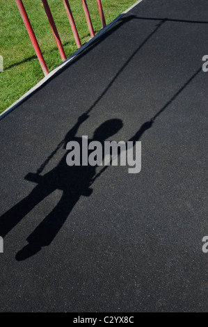 Shadow/Silhouette, von einem jungen Kind spielen auf einer Schaukel in einem Kinderspielplatz cast Stockfoto