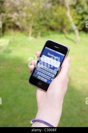 Person mit iPhone für Facebook-Nachrichten Stockfoto