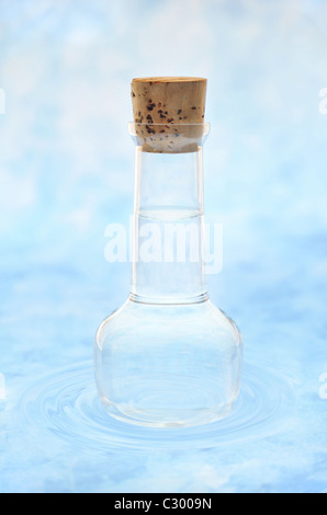 Flasche von sauberem Wasser in Wasser plätschert über farbigen Hintergrund Stockfoto