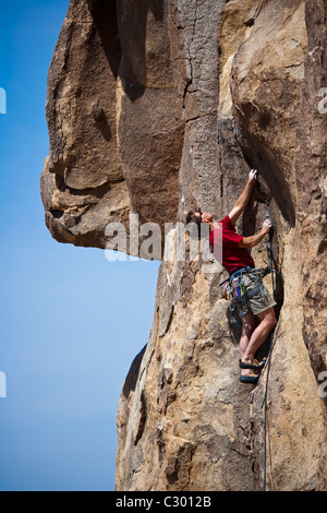 Männliche Felsen Kletterer kämpft für seinen nächsten Griff auf einem anspruchsvollen Aufstieg. Stockfoto