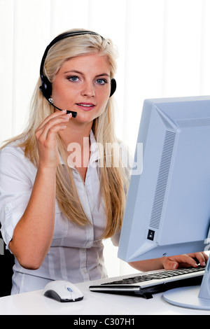 Frau am Computer mit Kopfhörer und Hotline Stockfoto