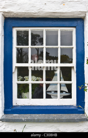 Segeln Yacht und Vase mit Blumen in hellen blauen Fenster von Rose Cottage bei Helston in Cornwall, Großbritannien Stockfoto