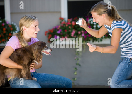 Teen Mädchen posiert mit ihrem Hund während bester Freund Foto mit Digitalkamera nimmt Stockfoto