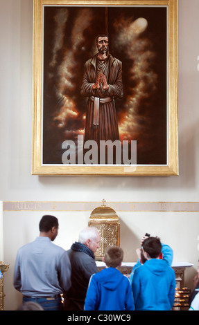 Besucher in St. Andrews Cathedral in Glasgow schauen Sie sich das Porträt von John Ogilvie des schottischen Künstlers Peter Howson Stockfoto