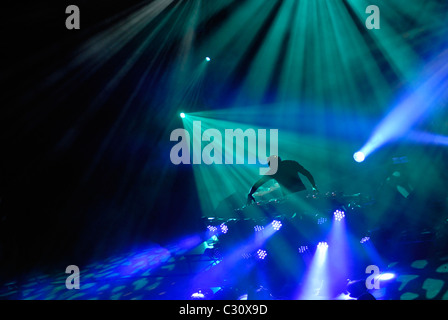 DJ mit Head-Set, eingehüllt in Lichter in einem Tanzclub, Diskothek oder Rave. Stockfoto