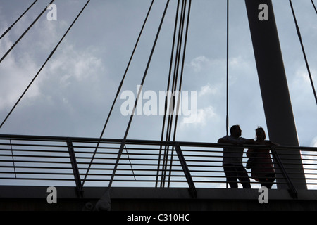 Silhouetten von zwei Menschen stützte sich auf den Schienen von The Golden Jubilee Bridge in London, England Stockfoto