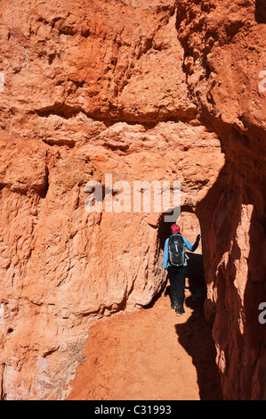 Weibliche Wanderer tritt Tunnel am Queens Garden Trail, Bryce Canyon National Park, Utah, USA Stockfoto