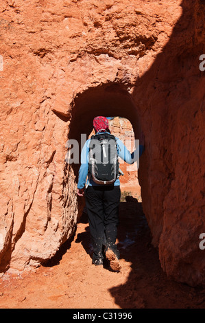 Weibliche Wanderer tritt Tunnel am Queens Garden Trail, Bryce Canyon National Park, Utah, USA Stockfoto