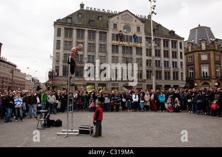 Eine Straße Entertainer führt seine Tat für eine Menge von Touristen, die vor Madame Tussauds Wax Museum Amsterdam gesammelt haben Stockfoto