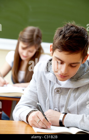 Porträt von kluger Kerl Notizen im Heft mit seinem Klassenkameraden hinter Stockfoto