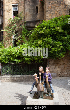 Zwei Mädchen sitzen auf der Statue von drei Gänse Sarlat la Caneda Dordogne Frankreich Stockfoto