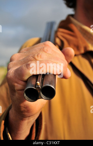 JÄGER SEIN FALTENDE AKTIEN GEWEHR ÜBER DER SCHULTER TRAGEN Stockfoto