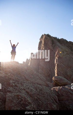 Ein junger Erwachsener steht triumphierend auf eine 500 ft Multi Pitch Trad Kletterroute in Colorado. Stockfoto