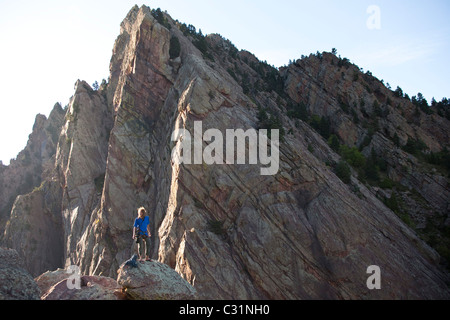 Ein junger Erwachsener steht triumphierend auf eine 500 ft Multi Pitch Trad Kletterroute in Colorado. Stockfoto