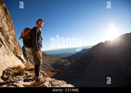 Ein junger Mann lächelt als die Sonnenaufgänge auf seine Bergtour. Stockfoto