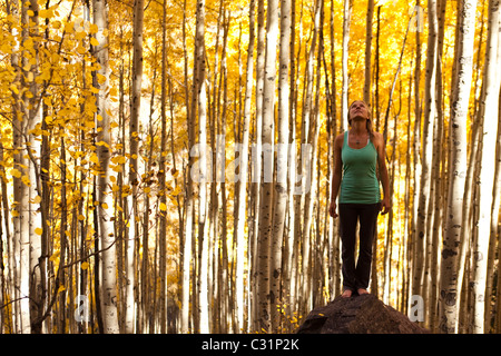 Eine junge Frau, die friedlich auf einem Felsen mitten in einem Meer von gold Aspen steht verlässt. Stockfoto