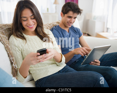 Paar mit Technologie auf Sofa zusammen Stockfoto