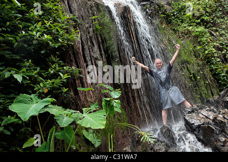 "COOLING OFF" UNTER EINEM WASSERFALL, TREKKING IM DSCHUNGEL, NATURSCHUTZGEBIET IN DER REGION VON BANG SAPHAN, THAILAND, ASIEN Stockfoto